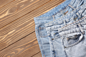 Sticker - Different stylish jeans on brown wooden background