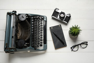 Wall Mural - Vintage typewriter with camera, houseplant and eyeglasses on white wooden background