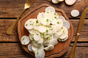 Wall Mural - Board with slices of fresh daikon radish on wooden background