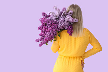 Canvas Print - Young woman with lilac flowers on color background, back view