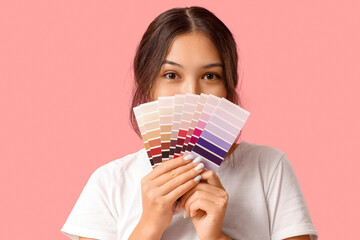 Wall Mural - young woman covering face with palette samples on pink background