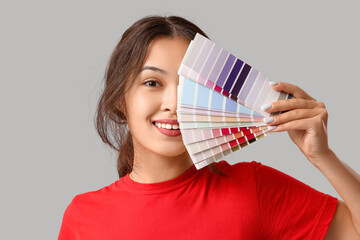 Poster - Beautiful young woman with covering face with different palette samples on grey background, closeup