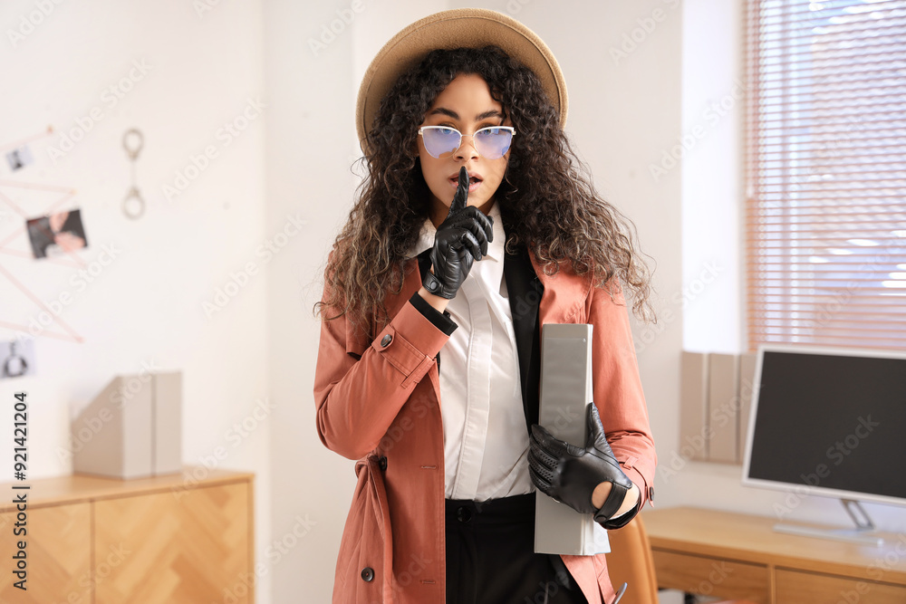 Female African-American spy with folder showing silence gesture in office