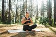 © Dusan - Young caucasian woman doing yoga stretching and meditating in forest