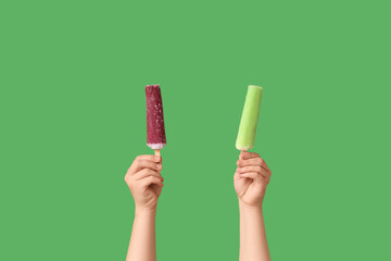 Wall Mural - Female hands with different sweet ice-cream on green background