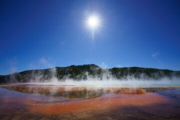 grand prismatic spring in yellowstone national park under a bright sun with clear blue skies, usa