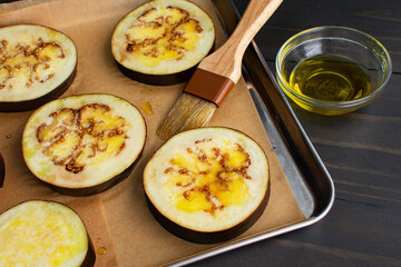 Wall Mural - Eggplant Slices Brushed with Olive Oil Close-up: Raw eggplant slices on a parchment paper lined sheet pan with a basting brush and olive oil