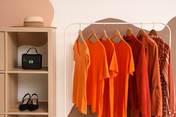 Wall Mural - Rack with orange clothes near colorful wall in room