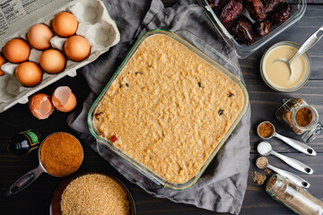 Wall Mural - Uncooked Middle Eastern Breakfast Bake: Breakfast casserole made with bulgur, dates, eggs, milk, and spices in a glass baking dish on wooden table