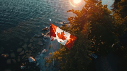 Canadian flag is waving in the wind on the shore of a lake with a golden sunset in the background