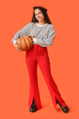 Wall Mural - Stylish young woman with fresh pumpkin on orange background