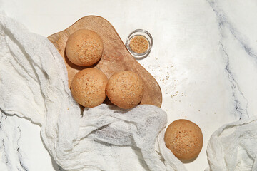 Wall Mural - Wooden board of fresh buns with sesame seeds on white background