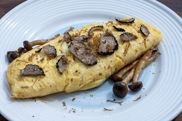 French omelette with mushrooms, fresh farmers eggs and black summer truffle mushroom in pieces for making truffle dishes with tasty aroma