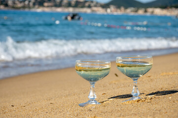 Summer time on French Riviera, two coupe glasses of champagne cremant sparkling wine on Pampelonne sandy beach near Saint-Tropez in sunny day, Var, vacation in France