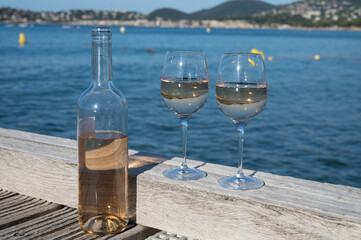 Tasting of cold rose wine from Provence outdoor on wooden yacht pier with view on blue water and white sandy beach Plage de Pampelonne near Saint-Tropez, summer vacation in France