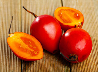 Wall Mural - Closeup of fresh orange tamarillo fruits with chopped slices on wooden background. Vitamin product