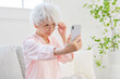 © siro46 - スマートフォンを見る老眼のシニア女性