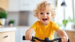 © Lens Legacy - A young boy dressed in a yellow shirt rides a yellow bicycle indoors, his curly blonde hair and wide smile reflecting pure happiness and excitement in a bright home environment.