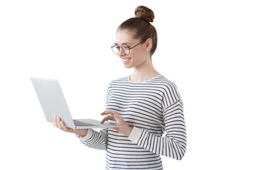 indoor photo of positive teenage girl standing with laptop, smiling at great content from social net