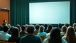 © D.e.a.r - A group of people seated in a conference room, attentively facing a blank projector screen, awaiting a presentation.