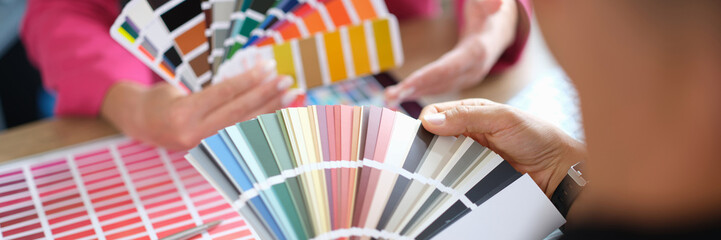 Woman designer holding fan of colourful paper samples in hand.