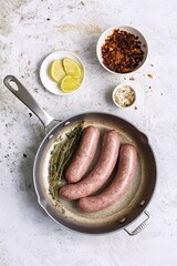 Wall Mural - Raw sausages in a pan with thyme. On a rustic background