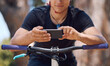 © Michael Cunningham/peopleimages.com - Sports, bicycle and hands of person with phone for training, adventure and exercise in nature. Fitness, cycling and cyclist on mountain bike with smartphone for navigation, website and health app