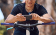 © Michael Cunningham/peopleimages.com - Sports, bicycle and hands of man with phone for training, adventure and exercise in nature. Fitness, cycling and person on mountain bike with smartphone for navigation, online website and health app