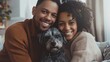 © Naknakhone - smiling diverse couple hugging their pet dog, smiling at camera, indoors. copy space for text.