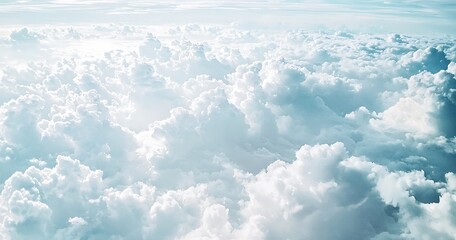 Aerial view of a vast expanse of fluffy white clouds against a pale blue sky.