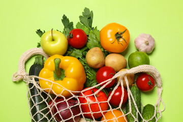 Poster - Delivery of vegetarian products. String bag with different vegetables and fruits on green background, top view