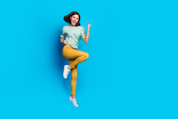 Wall Mural - Full size photo of satisfied girl wear turquoise blouse yellow pants flying win lottery clenching fists isolated on blue color background