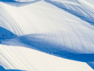 Wall Mural - Snow texture. Wind sculpted patterns on snow surface. Wind in the tundra and in the mountains on the surface of the snow sculpts patterns and ridges (sastrugi). Arctic, Polar region. Winter background