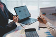 © amnaj - Business partners are analyzing financial documents with charts on a digital tablet during a meeting