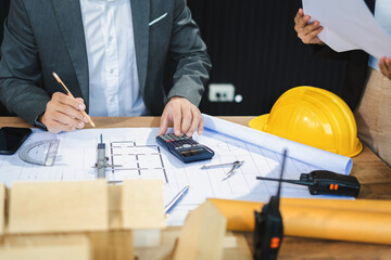 Wall Mural - Businessman working as a team discussing data working and tablet, laptop with on architectural project at construction site at desk in office.