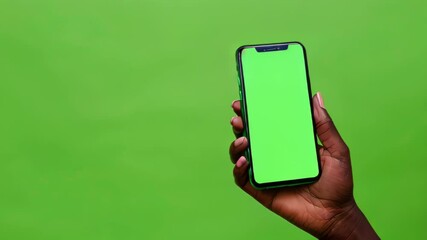 Close up hand holding smartphone with green screen over green background, apps mockup, template design presentation and advertising