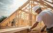 © Curioso.Photography - Construction worker assembling wooden beams at a building site.