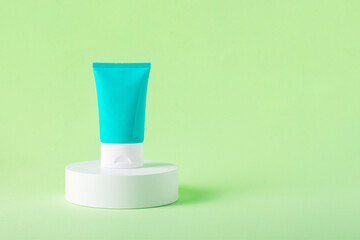 Blue cosmetic bottle, Skin care or sunscreen cosmetic with stylish props on green background.