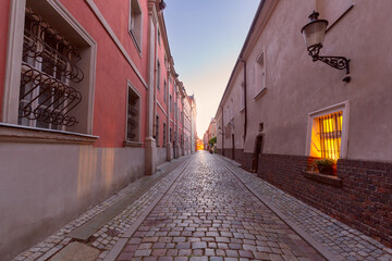 Wall Mural - A deserted narrow cobblestone street in the centre of Poznan at dawn.