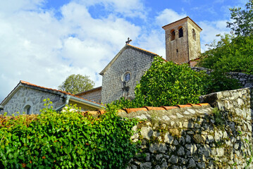 Wall Mural - Catholic Monastery of St. Anthony of Padua in Perast, Montenegro: view from the street of the ivy-covered stone wall, the church with a square bell tower and the buildings for housing the monks.