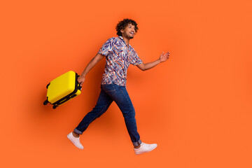 Sticker - Full body photo of attractive young man running hold baggage dressed stylish colorful clothes isolated on orange color background