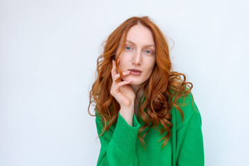 Canvas Print - A woman with red hair is wearing a green sweater and is looking at the camera