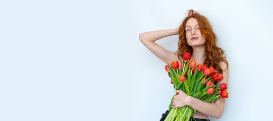 A woman with red hair is holding a bouquet of red tulips