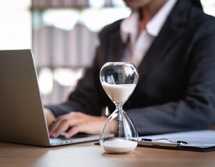 Close up of sandglass with business woman tired from working with laptop computer background. Relax Sleeping and taking nap concept. Business people and overtime workload theme. Office and home theme