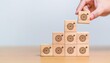 © Bonita - Hand holding wooden block with target aiming dart board and arrow up on table background. Business achievement objective goal and project progress growth value processing marketing financial concept