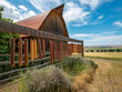 © MaxK - A barn with a fence in front of it. The fence has many wooden objects hanging from it