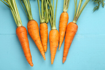 Wall Mural - Tasty ripe juicy carrots on light blue wooden table, flat lay