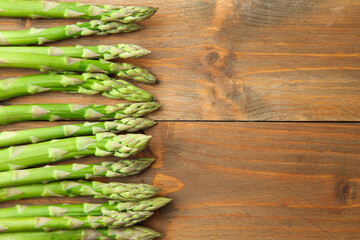 Sticker - Fresh green asparagus stems on wooden table, top view. Space for text