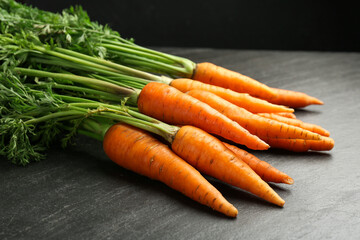 Wall Mural - Tasty ripe juicy carrots on dark gray textured table, closeup