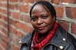 © Viam - Confident African woman smiling brick wall backdrop